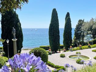 Sea view from the park over flowers, cypresses and a fountain
