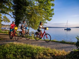 Three cyclists near the harbour, in the evening atmosphere on Lake Starnberg