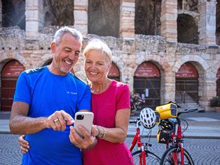 Cyclists with a phone in front of the arena in Verona