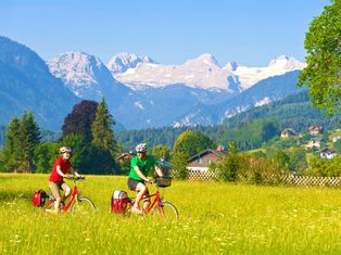 Radfahrer inmitten grüner Landschaft mit Bergpanorama
