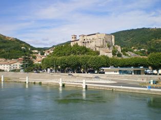 View across the river to the castle of la Voulte-sur-Rhone, with wooded hills in the background