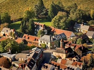 Luftaufnahme des Hotelkomplexes Auberge du Bon Laboureur in Chenonceaux mit traditionellen Gebäuden, roten Ziegeldächern und Weinbergen.