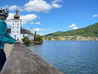 Radfahrerin blickt auf Schloss Ort am Traunsee