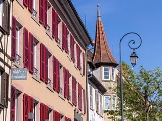 Hotel Le Colombier in Colmar mit traditioneller elsässischer Architektur mit roten Fensterläden, Fachwerkfassade und mittelalterlichem Turm.