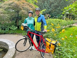Radler und Radlerin stehen mit Fahrrad in Rosengarten
