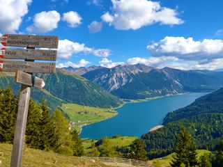 Hiking signpost with a view of Lake Reschen