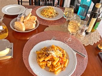 Two plates with pasta, bread and two glasses with white wine