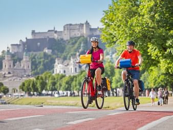 Radfahrer in Salzburg mit Festung Hohensalzburg im Hintergrund