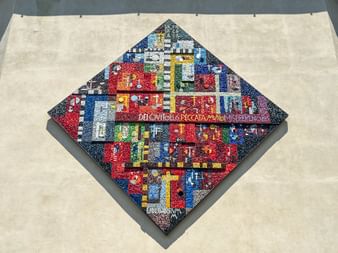 Rautenförmiges Mosaik mit bunten geometrischen Mustern in Rot, Blau, Gelb und Weiß auf grauer Fläche in Spilimbergo.