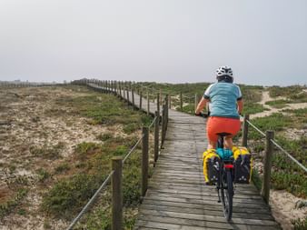 Active holidaymaker with rental bike on the wooden walkway in Furadouro
