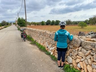 Radfahrerin blickt in die Landschaft in Cala Santanyi