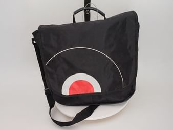 Black messenger bag hanging on a hanger with geometric circular design featuring white and red concentric circles on the front flap.