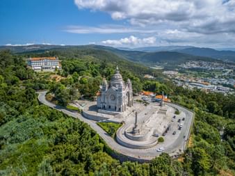 Aerial view of Basilica da Santa Luzia on a hilltop in Viana do Castelo, surrounded by green forests and mountains in the background.