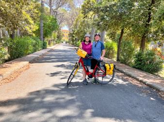 Zwei Personen stehen auf einer Straße mit einem Eurobike Fahrrad und machen Pause in der Toskana, umgeben von Bäumen