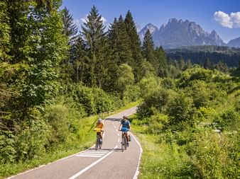 Two cyclists on the cycle path in the canal valley near Tarvisio with the mountains in the background