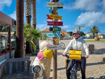 Cyclist next to signpost in Sagres