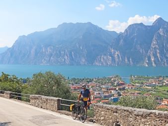 Cyclists on the Adige cycle path with a view of the Lake Garda