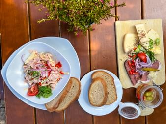 Bavarian snack spread with cold cuts, cheese, bread, and pickles on wooden boards. Includes meat salad, sliced sausage, and fresh vegetables.