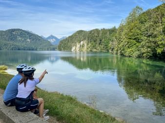 Radfahrerin zeigt auf Alpsee