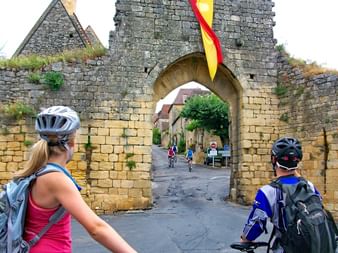 Cyclists in front of the Porte del Bos in Domme