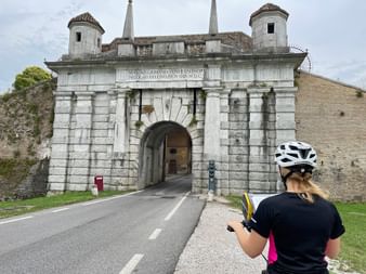 Cyclist in front of the city gate of Palmanova