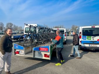 Three people inspecting a trailer loaded with bicycles at Eurofun Touristik Training Days 2026. Two vans with bike and hike branding visible.
