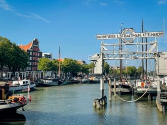 Historischer Hafen Wolwevershaven in Dordrecht mit vertäuten Booten und historischem Straatman-Fabrikschild. Traditionelle niederländische Häuser säumen das Ufer.