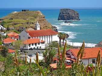View of the church of Porto da Cruz, in the background a free-standing rock in the sea