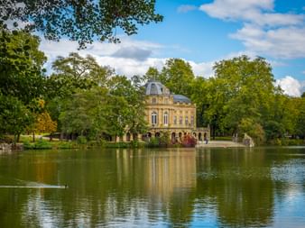 Seeschloss Monrepos, ein barockes Schloss mit gelber Fassade und Kuppel, spiegelt sich in einem ruhigen See umgeben von grünen Bäumen.