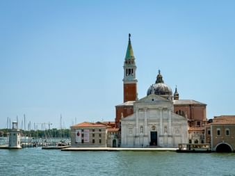 Basilika San Giorgio Maggiore mit weißer Marmorfassade und rotem Backsteinturm auf einer Insel in Venedig, umgeben von blauem Wasser und Marina.