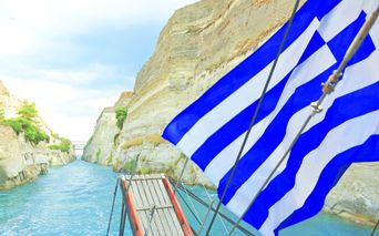 A boat with a Greek flag passing through the Corinth Canal
