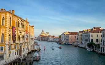 Blick entlang des Canal Grande in Venedig mit historischen Palästen zu beiden Seiten und der weißen Kuppel der Kirche Santa Maria della Salute.