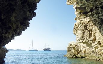 View from a rock cave of two sailing ships by the sea