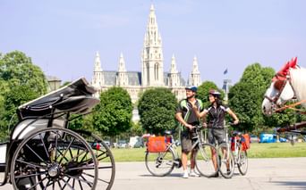 Radler vor Wiener Rathaus und Blick auf Fiaker