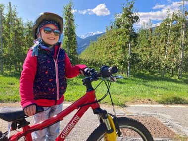 Child with bike in front of a natural backdrop