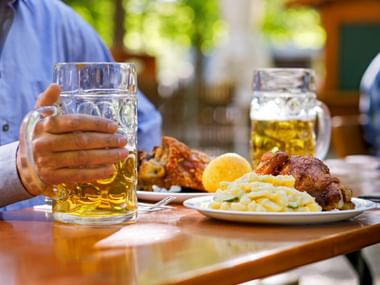 Mann genießt Schweinshaxe mit Bier in einem bayerischen Biergarten