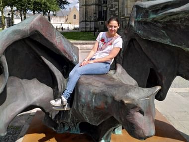 Frau in legerer Kleidung auf einer Drachenstatue