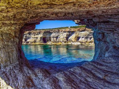 Blick durch eine Felshöhle auf das Meer und Klippen