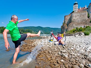 Radfahrer an der Donau vor Schloss Schönbühel