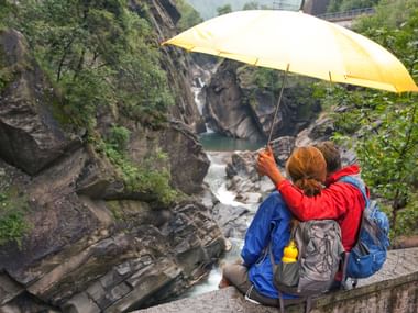 trotz leichtem Regen geniesst ein Pärchen den Fluss und sie sitzen auf einer Mauer