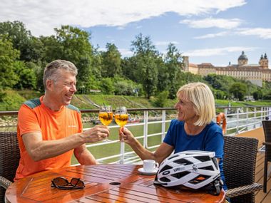 A couple with Aperol on the ship's terrace, Melk Abbey in the background