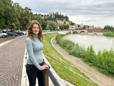 Woman by the river in front of the Ponte Pietra in Verona.
