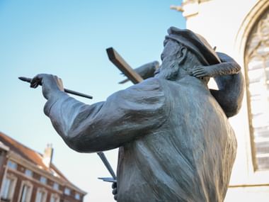 Bronzestatue von Pieter Bruegel dem Älteren mit Pinsel, von unten fotografiert vor blauem Himmel in Brüssel, Flandern.