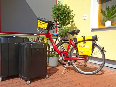 Fahrrad und Gepäck vor Hausmauer