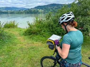 Eine Radfahrerin schaut am Völkermarkter Stausee in ihre Reiseunterlagen.