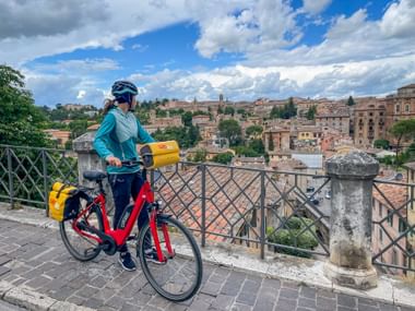 Radfahrer mit rotem Leihrad blickt auf Altstadt Perugia
