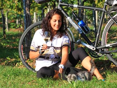 Radfahrerin sitzt mit Weinglas vor ihrem Rad