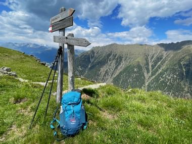 Rucksack am Wegweiser vor Bergkulisse