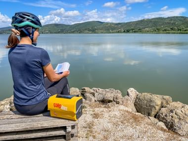 Radfahrerin am Trasimeno See mit Reiseunterlagen und gelber Radtasche