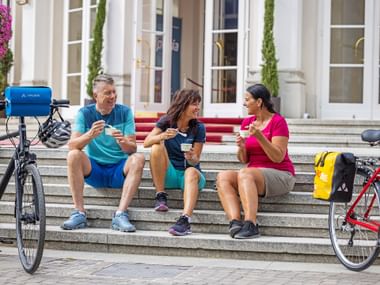 Bike break at the Kurhaus in Merano Two women and a man take a break from cycling on the steps of the Merano Kurhaus with an ice cream in their hands